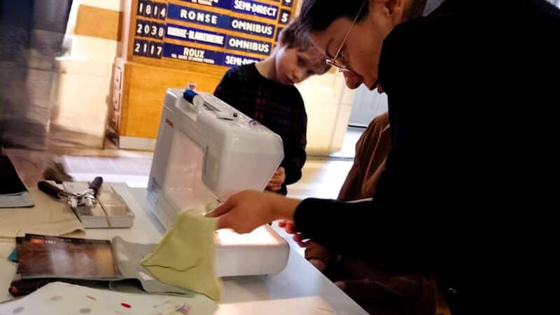 Atelier : femme et enfant apprenant à coudre sur une machine à coudre