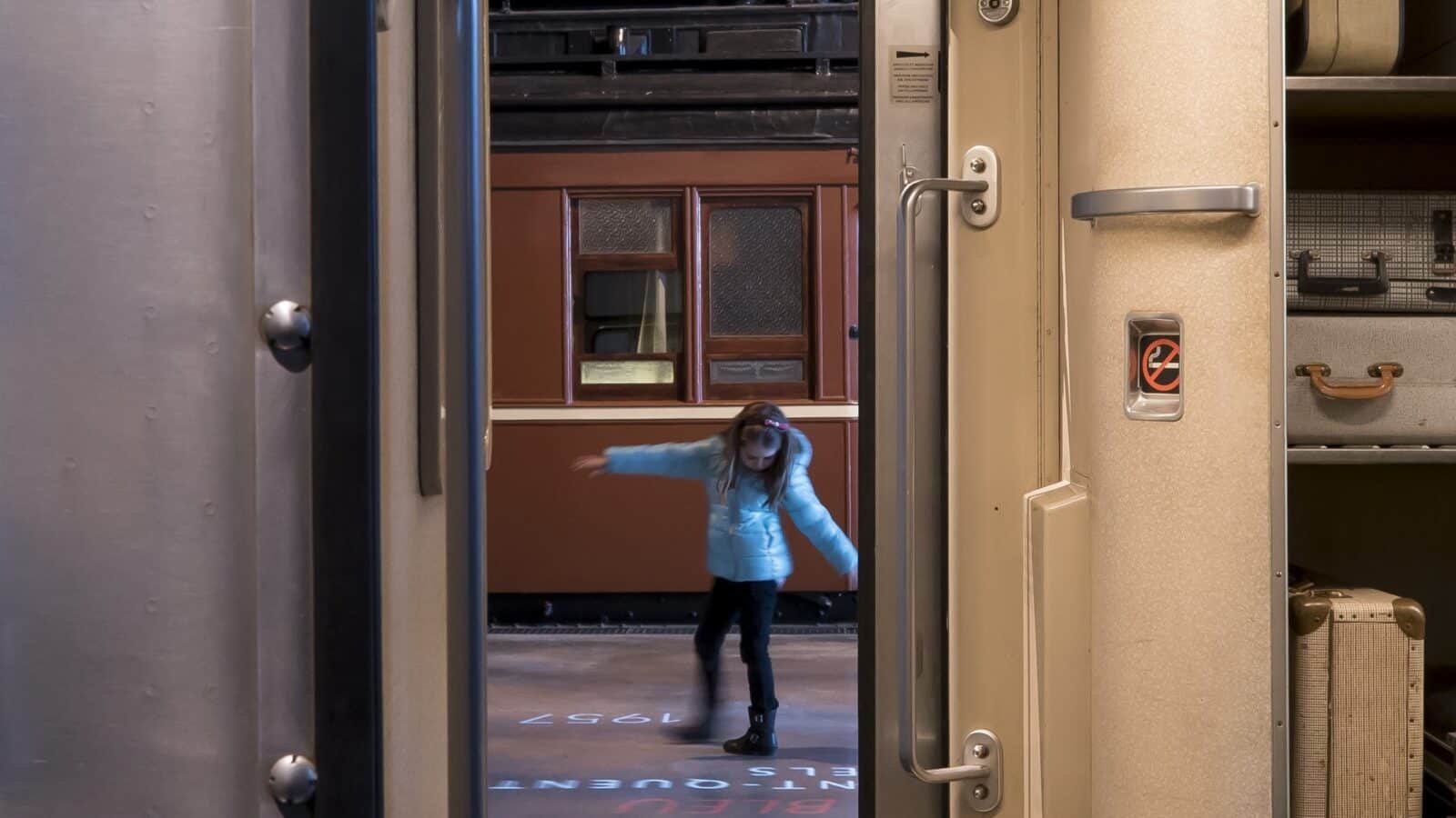Meisje in blauwe jas stapt uit treinwagon tijdens herfstreis